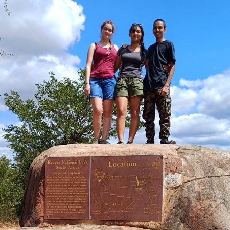 Three learners on a rock during a school tour